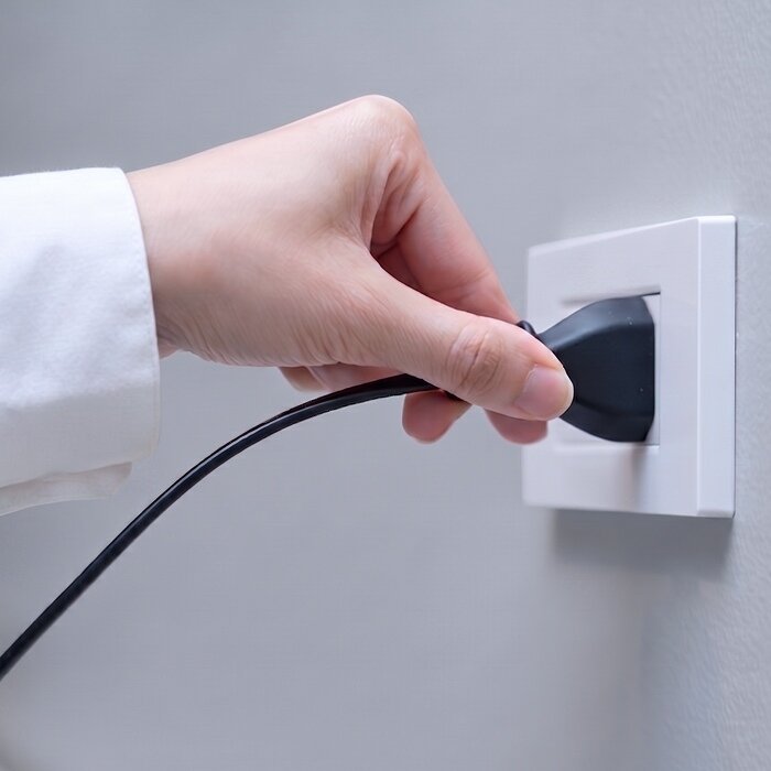 Hånd som kobler et elektrisk apparat til en stikkontakt